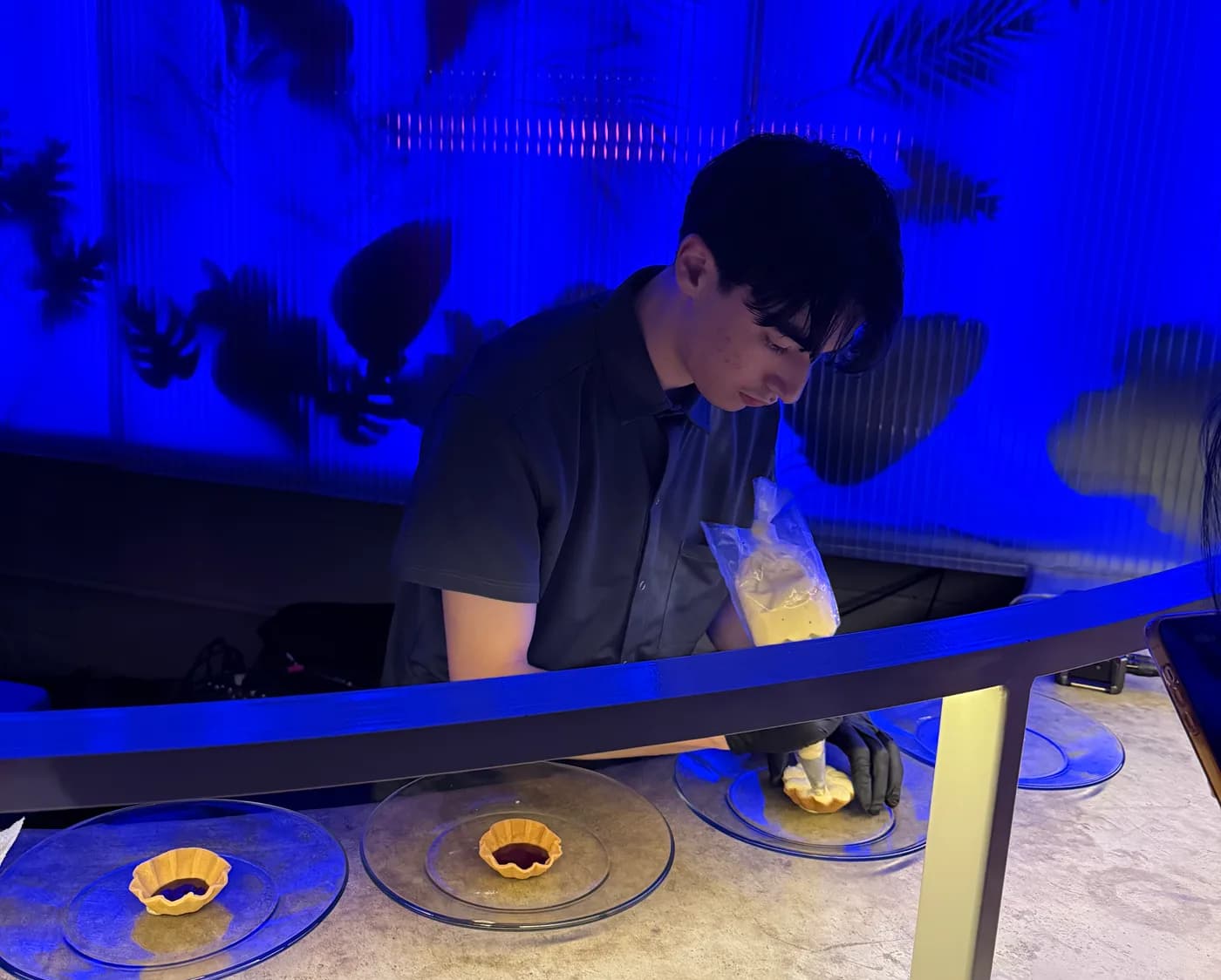 A pastry chef finishing individual desserts at an evening gathering
