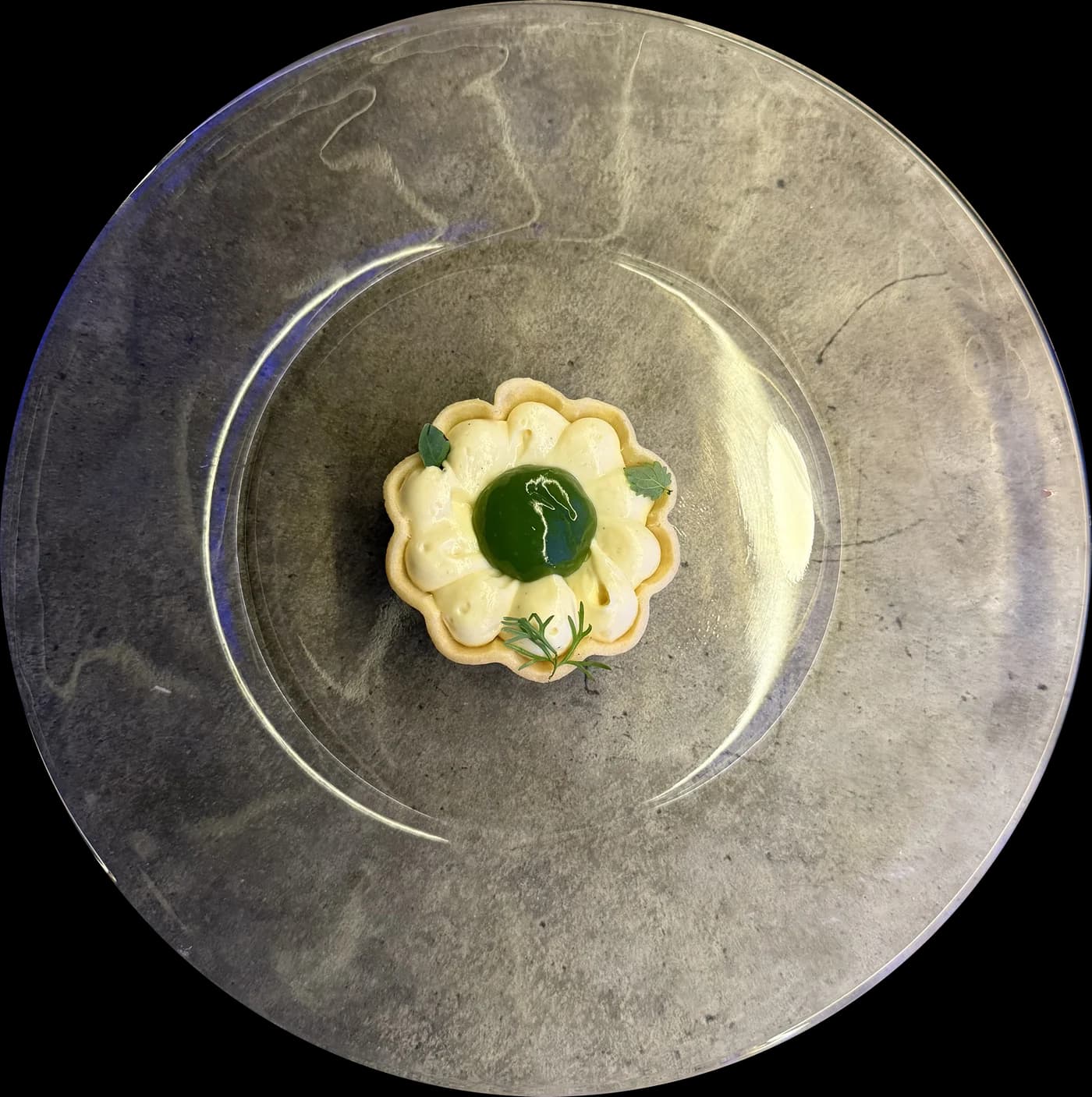 An overhead view of a small, flower-shaped dessert on a ceramic plate