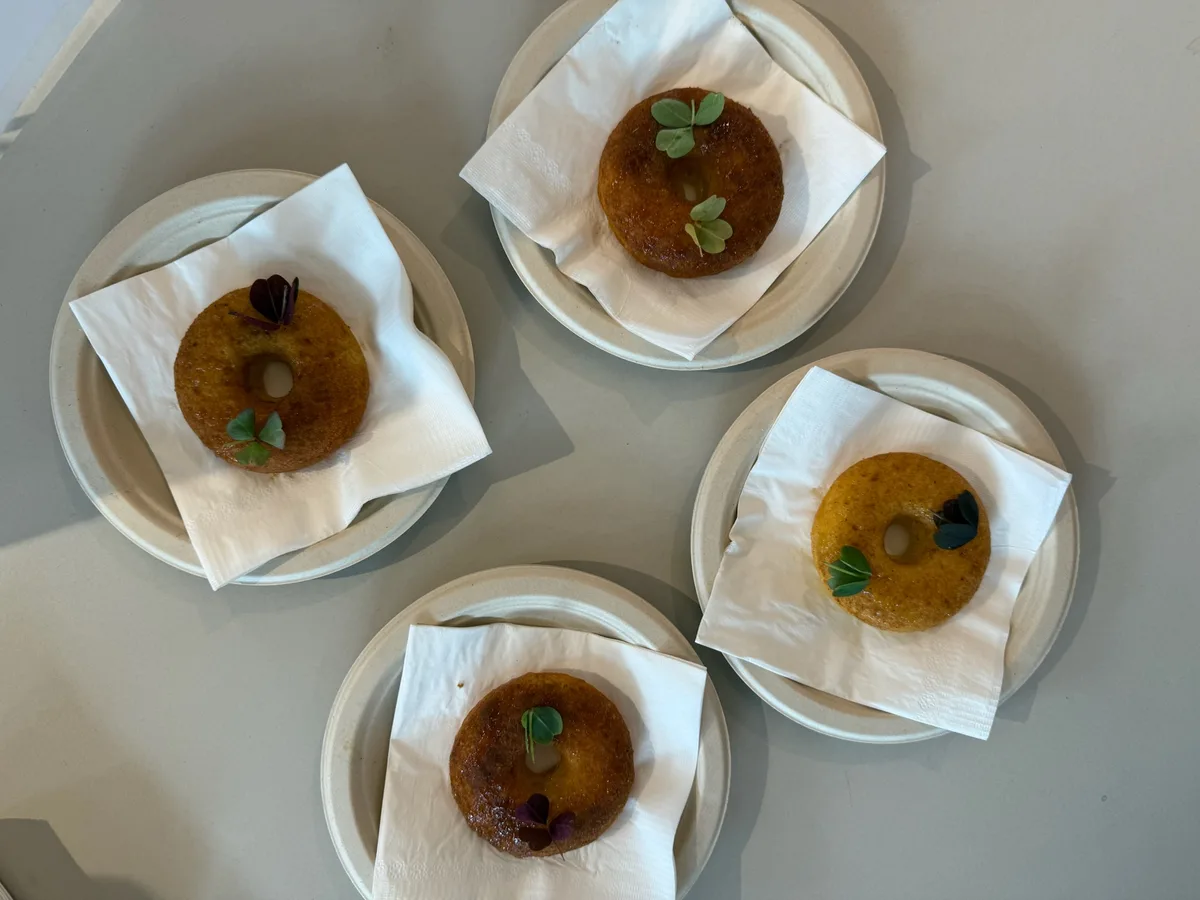 Finished donuts on white plates, each topped with a green leaf